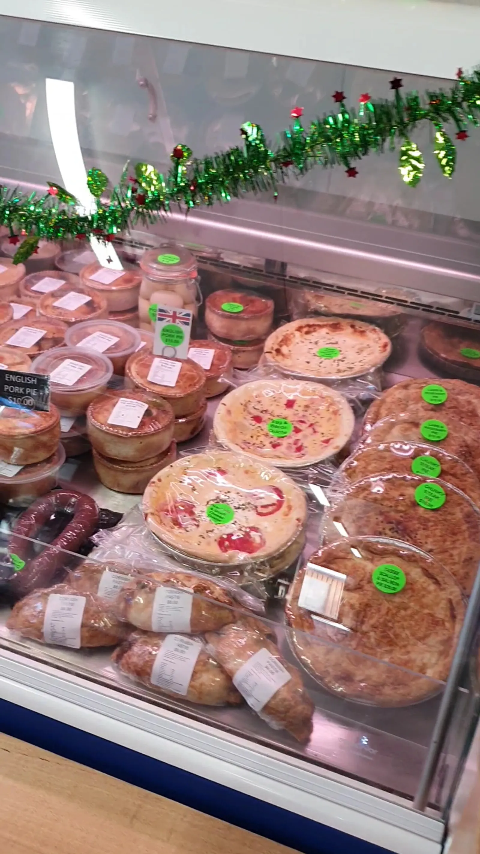 Glass display case packed with pies, quiches and sausages at Hill Top Farm Meats butcher counter
