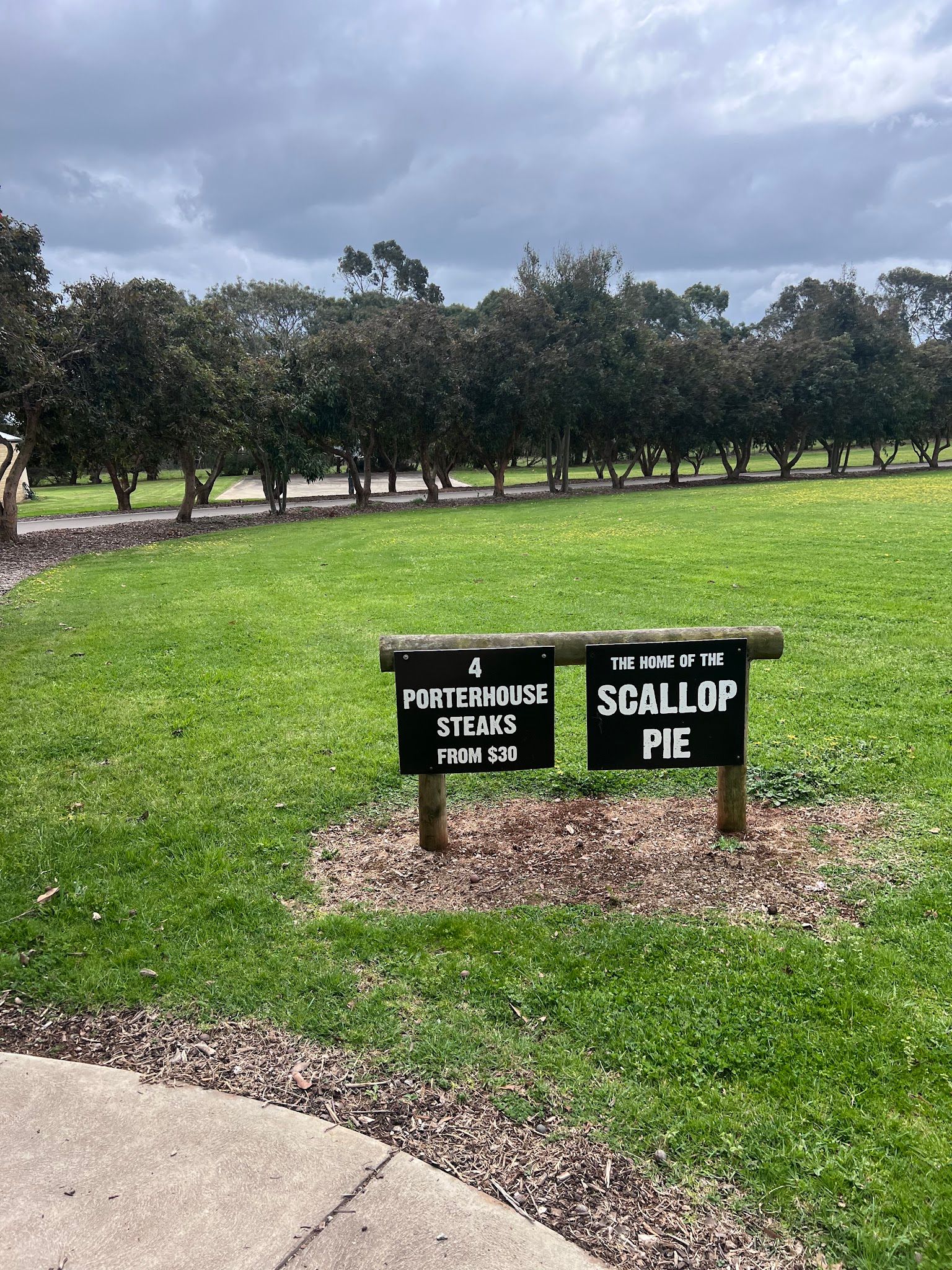 Roadside signs: 4 Porterhouse Steaks from $30 and Home of the Scallop Pie on a green Phillip Island lawn